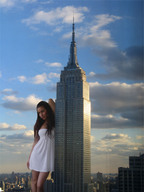 giantess collage city black_hair leaning_against_building white_dress looking_at_viewer empire_state_building rooftop_view leaning_on_skyscraper