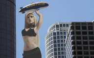 breasts giantess city blonde long_hair bra buildings lips navel hand belly skyscraper hot lipstick looking_up grabbing red_lips hot_air_balloon straight necklace belt zeppelin airship
