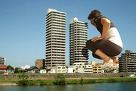 giantess collage destruction clothed buildings brunette unknown_artist squatting river crouching looking_in waterway