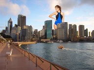 breasts giantess city swimsuit water buildings brunette ponytail hand looking_down boats sky smirking