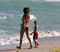 gentle collage black_hair long_hair swimsuit clothed beach barefoot ocean mini_giantess walking sunglasses lowerrider swim_trunks
