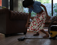long_hair clothed skirt brunette sandals reaching running shrunken_man maid_uniform chair vacuum runswithferrets shirt sofa digital_render wood_floors