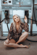 gentle collage blonde long_hair clothed barefoot cleavage sitting shrunken_man looking_at_viewer gas_station