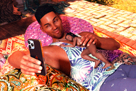 gentle nude male barefoot brunette smiling lying_down hand shrunken_woman dark_skin cellphone chest digital_render bare_legs guys_and_dolls