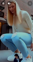 gentle giantess city blonde long_hair clothed jeans shoes looking_down crouching sweater sidewalk ai_art shrunken_man