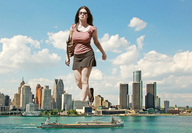city mega long_hair brunette walking sunglasses short_skirt boats skyscrapers flip_flops bag ships